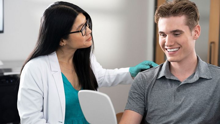 Een jonge vrouw die lacht met haar aligner in haar hand