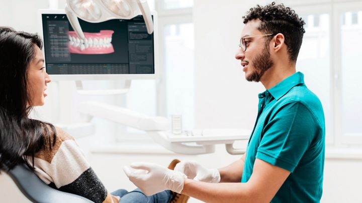 En tannlege som viser en pasient en behandlingsplan på nettbrett
