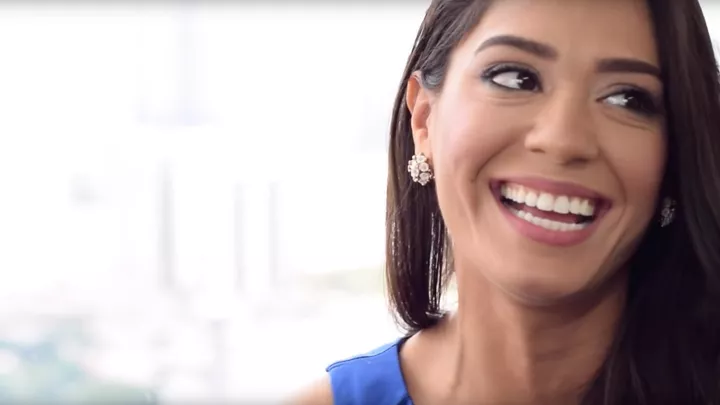A young woman smiling and holding her aligner