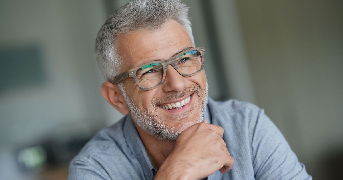 A man with mini dental implant treatment showing his smile