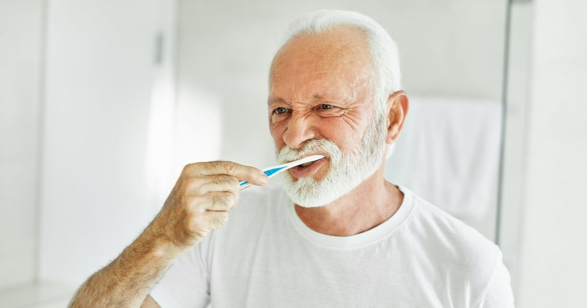 man brushing his teeth in the mirror