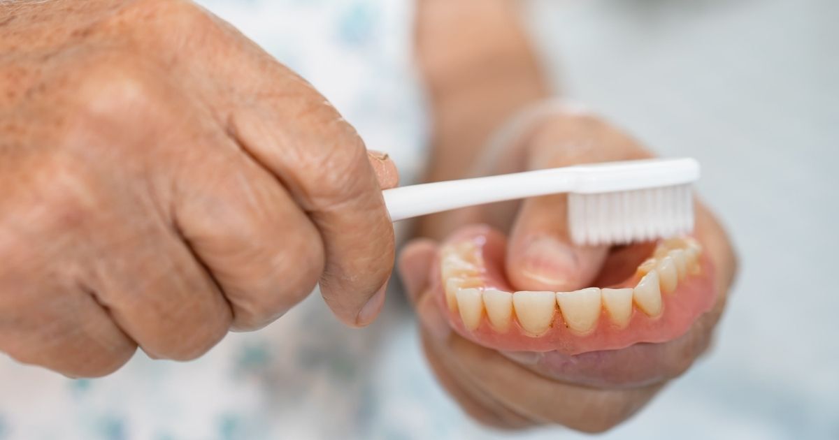 A man cleaning his dentures in the bathroom sink